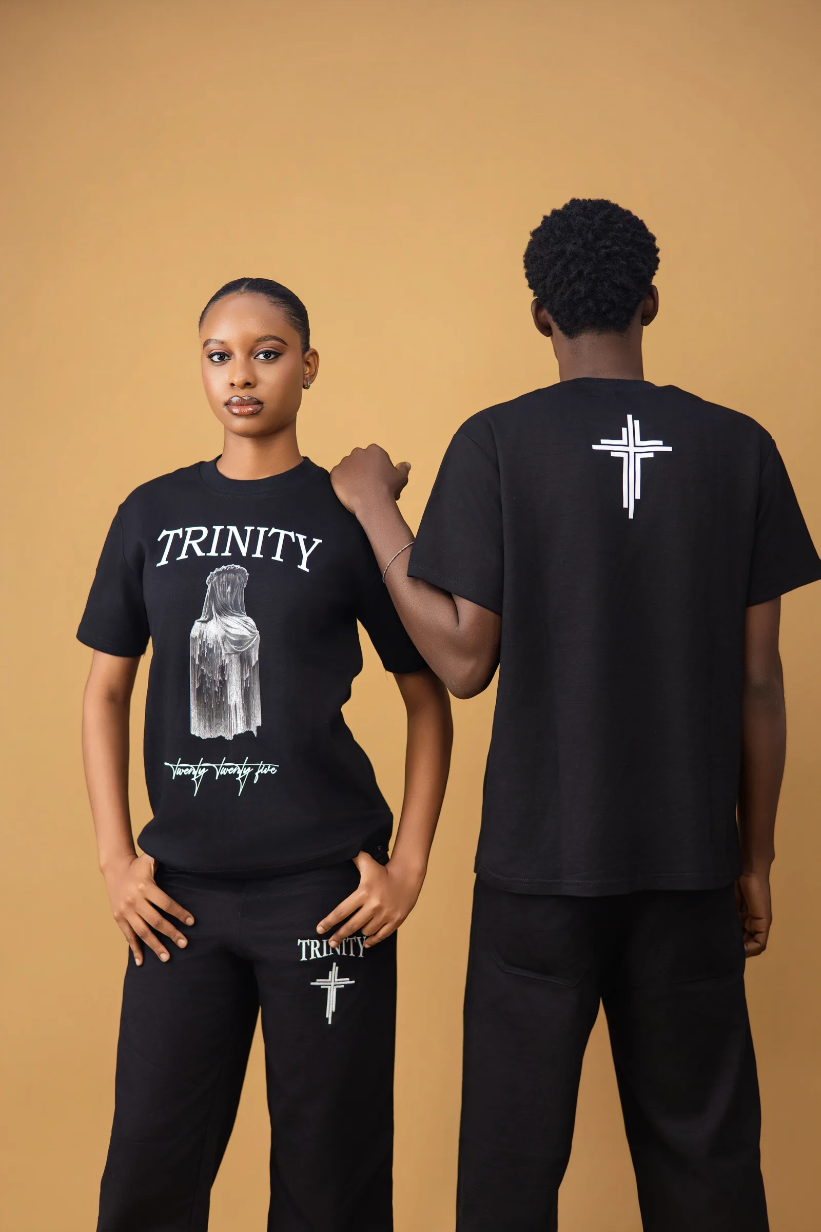 Both models wearing the black shirt and pants, one facing front and one facing back
